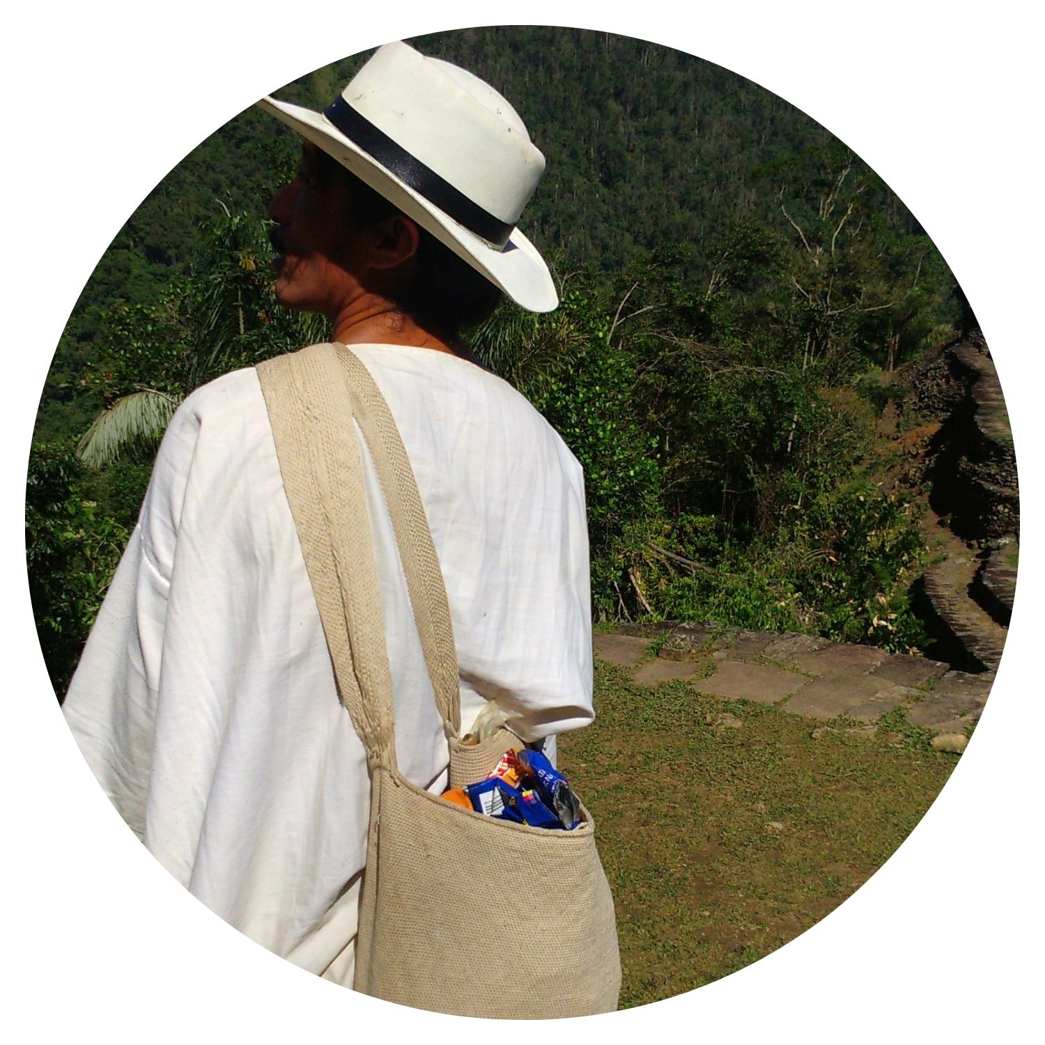 Jeune homme avec chapeau en rafia et sac à dos, contemplant la beauté naturelle de la Colombie.