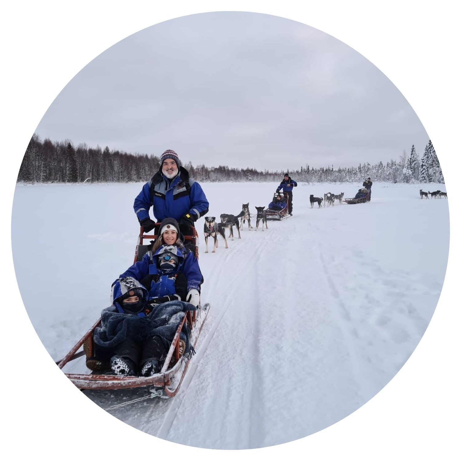 Une famille répartie dans plusieurs petits traîneaux traverse une montagne enneigée en Finlande, offrant une expérience hivernale inoubliable.