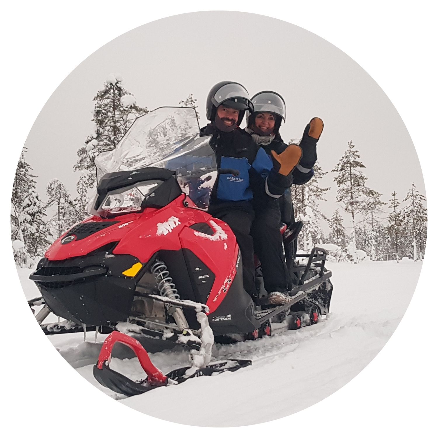 Un couple profite d'une aventure hivernale sur une moto de ski au cœur de la forêt enneigée de Finlande, une expérience unique en famille.