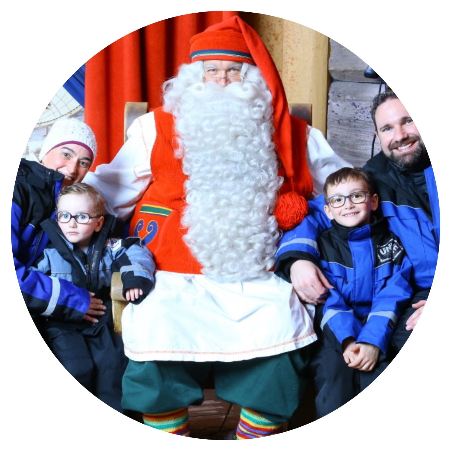 Une famille heureuse prend une photo avec un monsieur déguisé en Père Noël, les petits garçons souriants dans les bras de leurs parents, capturant la magie de Noël en Finlande.