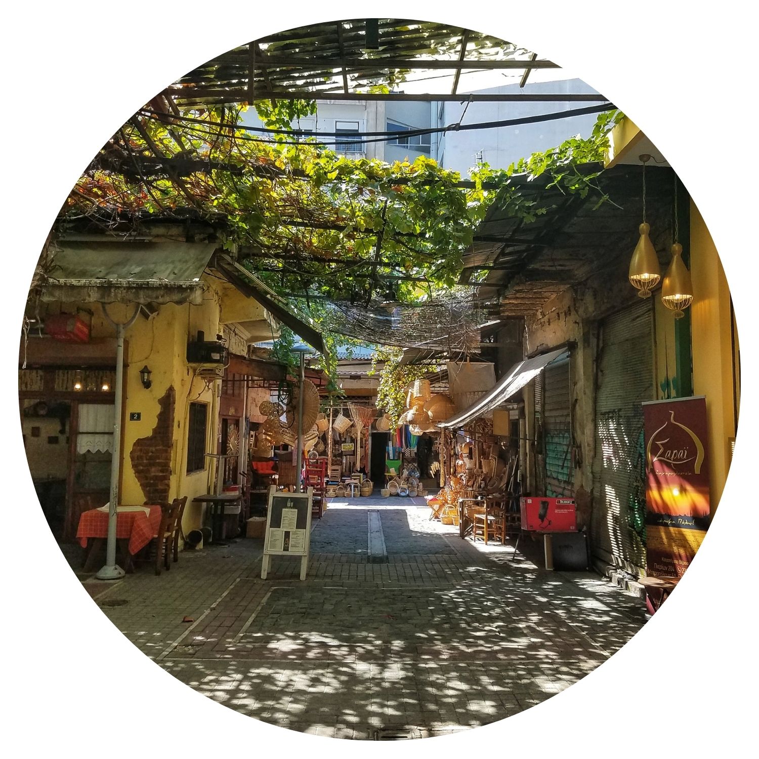 Marché artisanal pittoresque en Grèce, avec des petits couloirs ombragés par des feuilles d'arbre et baignés de rayons de soleil, offrant une ambiance authentique.