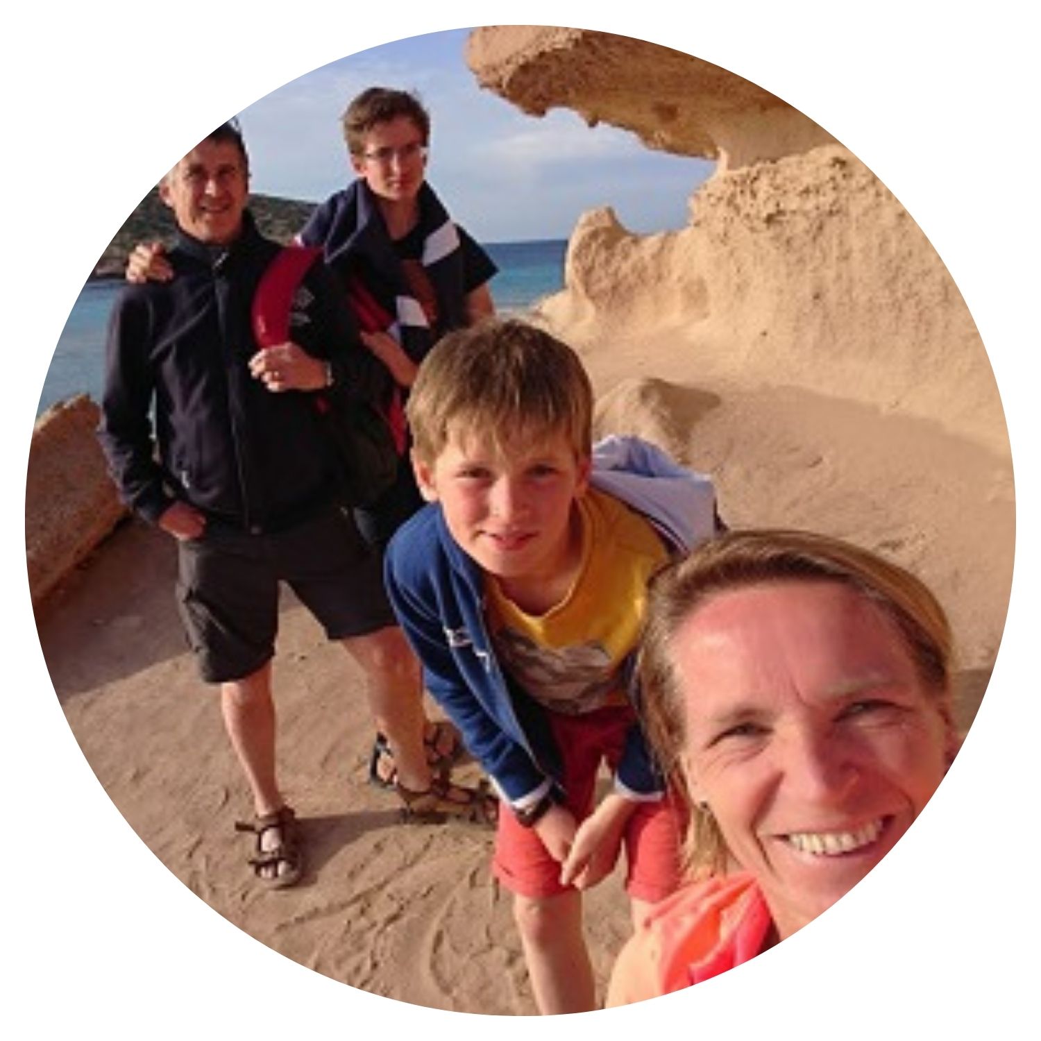Une petite famille, composée de deux fils et de leurs parents, prend un selfie devant un monument historique à Ibiza, capturant des souvenirs précieux de leur voyage en famille.