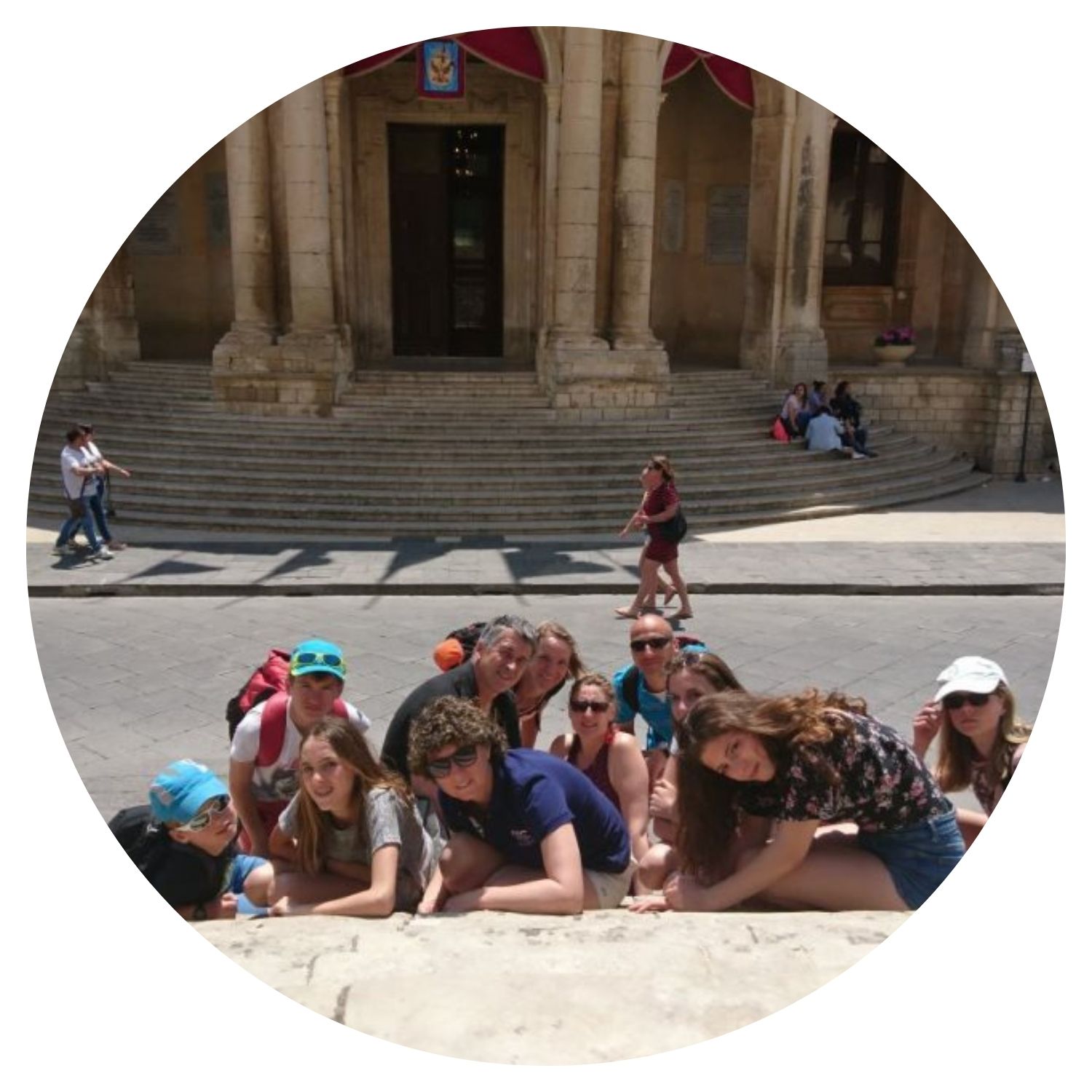 Un groupe de jeunes voyageurs en Italie prend une photo joyeuse devant un bâtiment emblématique, capturant l'enthousiasme et la camaraderie de leur voyage sur mesure.
