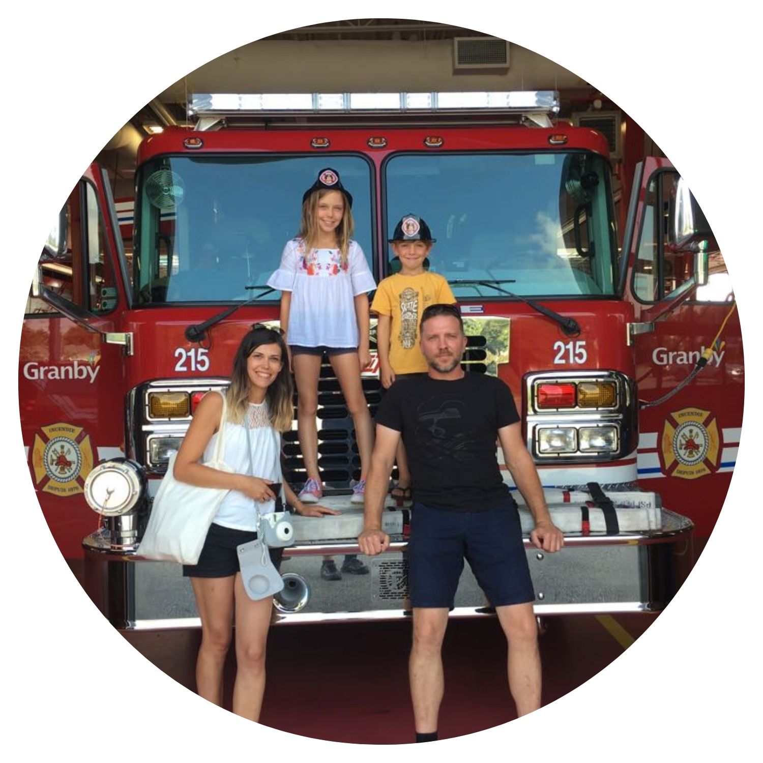 Voyage au Québec en famille avec l'avis de Julie L, une jeune famille posant devant un camion de pompier avec des casques de pompier.