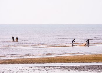 Pêcheurs à Zanzibar tirant des filets sur une plage lors d'un voyage en famille.